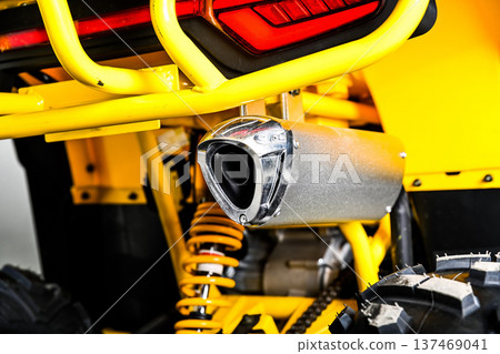 Close up of a silver exhaust pipe on a yellow powerful all terrain vehicle atv quad bike with visible suspension and tire for off road racing outdoors Close up of a silver exhaust pipe on a yellow powerful all terrain vehicle atv quad bike with visible suspension and tire for off road racing outdoors 137469041