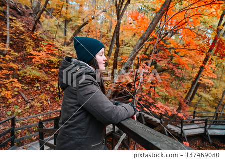 Russian woman 35 years old solo traveler with closed eyes enjoying forest aroma on autumn stairs focusing on wellness relaxation mindfulness and inner peace 137469080