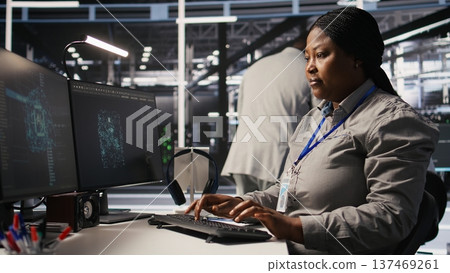 Data center programmer coding on PC, doing software updates for AI visualization systems. African american woman in server room optimizing infrastructure using artificial intelligence, camera A 137469261