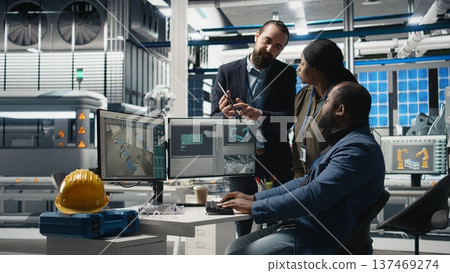 Multiethnic team of experts collaborating in a solar panel power plant, reviewing blueprints and production line metrics to ensure clean energy manufacturing and sustainability. Camera A. 137469274