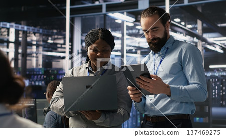 Data scientists working together in server room, reviewing neural network code and LLM visualization dashboards. Team of IT experts coordinating tasks, monitoring AI system performance, camera A Data scientists working together in server room, reviewing neural network code and LLM visualization dashboards. Team of IT experts coordinating tasks, monitoring AI system performance, camera A 137469275