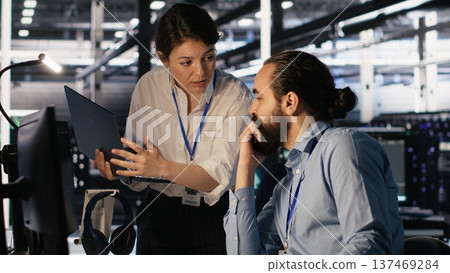 Data center admins working together, collaborating on neural network software development. Teamworking server hub colleagues implementing artificial intelligence technology in workplace, camera A 137469284