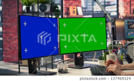 Businesswoman in a modern workplace types on a keyboard next to chroma key, using a creative agency office setup for digital media work. High tech workstation perfect for tasks. Camera A. Businesswoman in a modern workplace types on a keyboard next to chroma key, using a creative agency office setup for digital media work. High tech workstation perfect for tasks. Camera A. 137469324