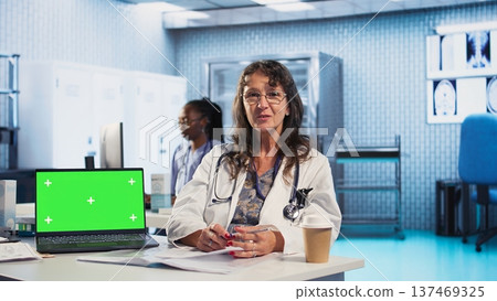 Senior medic consulting ill man in cabinet with isolated mockup screen, checking the hospital records to do another x ray scan interpretation. Old patient discuss with his physician. Camera A. Senior medic consulting ill man in cabinet with isolated mockup screen, checking the hospital records to do another x ray scan interpretation. Old patient discuss with his physician. Camera A. 137469325