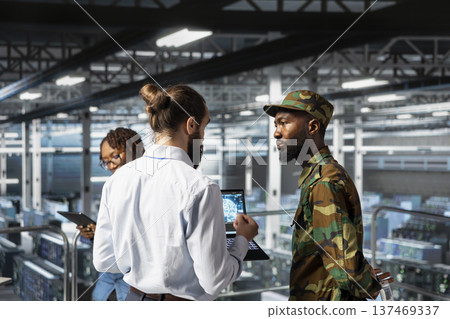 Soldier in server room uses geospatial data to support evacuation during emergency operations. Military data center personnel in uniform coordinating disaster response logistics control. 137469337
