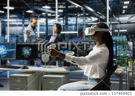 Server farm worker using virtual reality tech, deploying deep learning tools to automate repetitive workflows. Data center technician wearing VR headset managing datasets used in AI training Server farm worker using virtual reality tech, deploying deep learning tools to automate repetitive workflows. Data center technician wearing VR headset managing datasets used in AI training 137469403