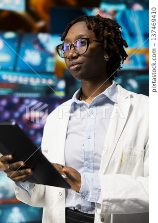 Healthcare researcher using tablet app, looking at medical data, working on disease prevention research. Scientist doing treatment development, looking at patient scans on touchscreen device 137469410