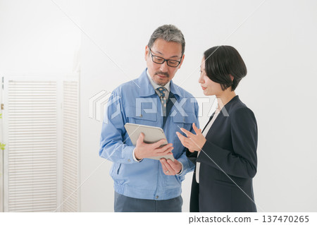A man in work clothes and a woman in a suit having a meeting A man in work clothes and a woman in a suit having a meeting 137470265