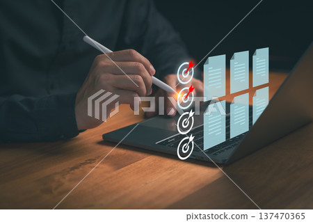 Person using a digital pen on a laptop to targets and review digital documents, illustrating workflow optimization, task completion, productivity planning, and data organization in a modern workspace. 137470365