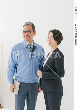 Smiling man in work clothes and woman in suit Smiling man in work clothes and woman in suit 137470918