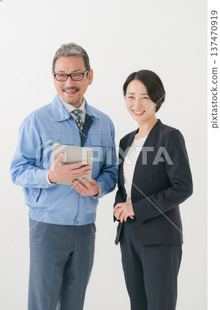 Smiling man in work clothes and woman in suit Smiling man in work clothes and woman in suit 137470919