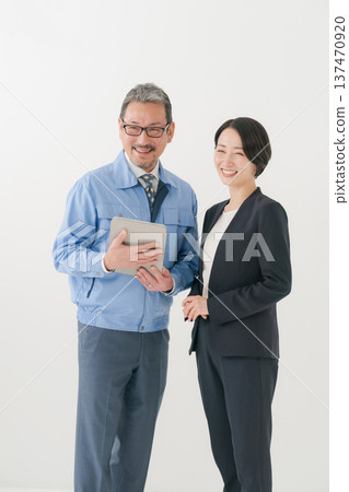 Smiling man in work clothes and woman in suit Smiling man in work clothes and woman in suit 137470920