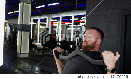 Man training on cable rowing machine in gym 137470936