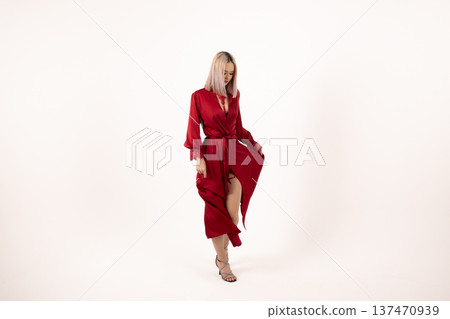 Woman in red robe posing against white background Woman in red robe posing against white background 137470939