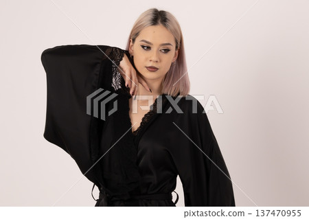 Woman in black silk robe posing with hand near face 137470955