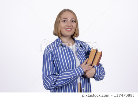 Smiling woman in blue shirt holding a stack of books 137470995