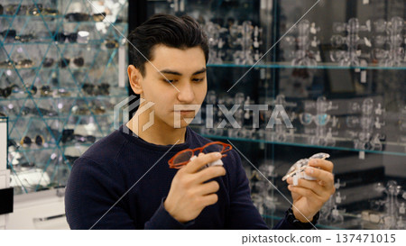 Man inspecting new eyewear in optics store Man inspecting new eyewear in optics store 137471015