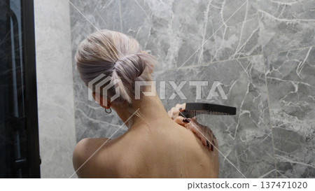 Woman shaving her back with electric shaver Woman shaving her back with electric shaver 137471020