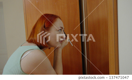 Woman applying makeup or cream near a mirror at home Woman applying makeup or cream near a mirror at home 137471047