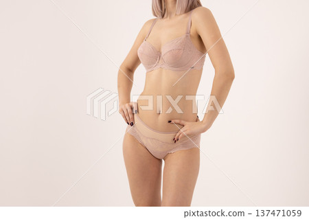 Woman in beige lingerie posing on light background Woman in beige lingerie posing on light background 137471059