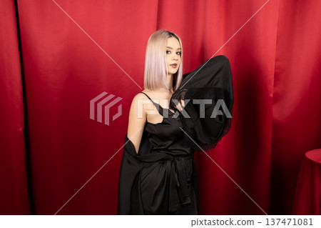 Woman in black silk robe posing on red background Woman in black silk robe posing on red background 137471081