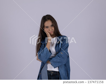 Young woman in blue shirt looking sad and thoughtful Young woman in blue shirt looking sad and thoughtful 137471158