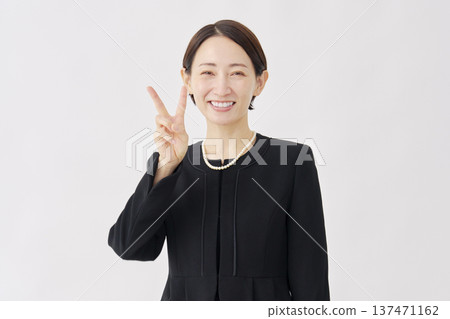 Woman in mourning clothes making a peace sign on a white background 137471162