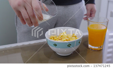 Person pouring milk into cereal bowl for breakfast 137471245