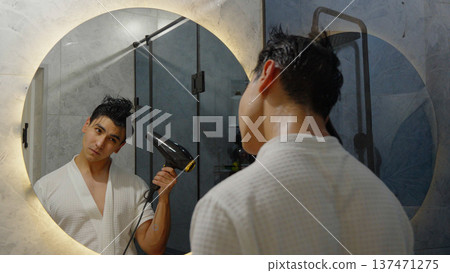 Person blow drying their hair in front of a mirror Person blow drying their hair in front of a mirror 137471275