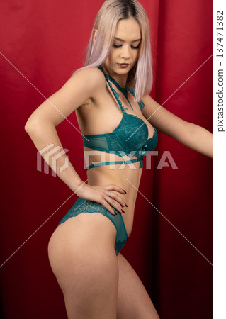 Young woman in teal lingerie posing near red drapes Young woman in teal lingerie posing near red drapes 137471382