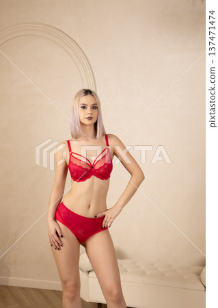 Young woman in red lingerie posing against a wall Young woman in red lingerie posing against a wall 137471474