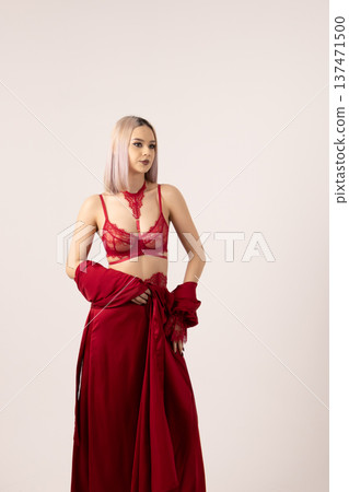 Woman in red lace lingerie and robe posing in a studio 137471500