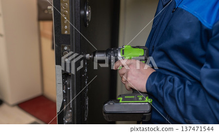 The technician installs a smart electronic lock on the front door. The technician installs a smart electronic lock on the front door. 137471544