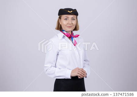 Woman flight attendant in uniform and hat looking at camera Woman flight attendant in uniform and hat looking at camera 137471586