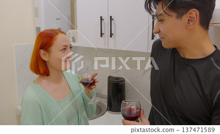 Young couple talking and drinking wine in the kitchen 137471589