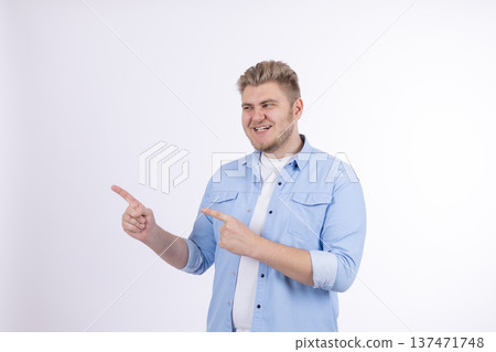 Man in blue shirt pointing to the side with one hand 137471748