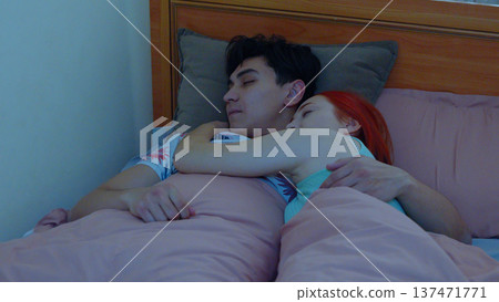 Exhausted young man sleeping in bed with head on pillows Exhausted young man sleeping in bed with head on pillows 137471771