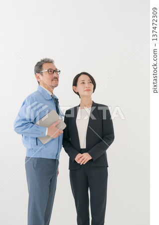 一個穿著工作服的男人和一個穿著西裝的女人抬頭看著地面。 137472309