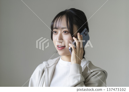 A smiling young woman talking on a smartphone A smiling young woman talking on a smartphone 137473102