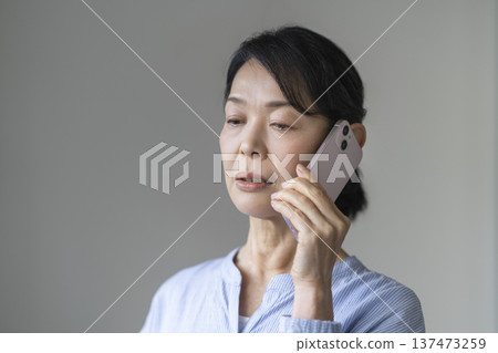 A woman in her late 50s talking on a smartphone A woman in her late 50s talking on a smartphone 137473259