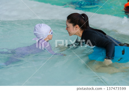 preschool child girl playing and swimming with her mother in pool 137473599