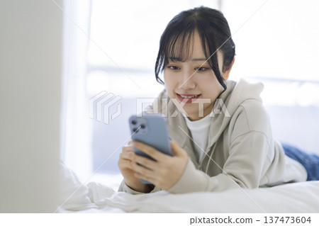 Smiling young woman looking at her smartphone screen 137473604