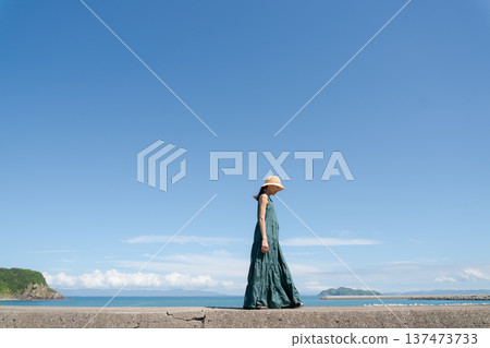 A young woman in a one-piece dress against the blue sky 137473733