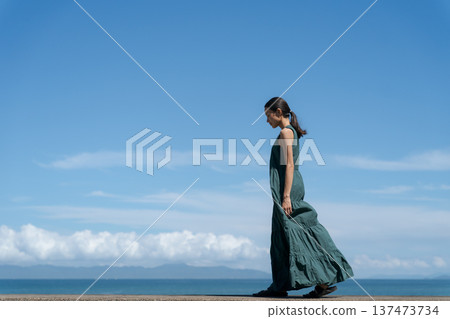 A young woman in a one-piece dress against the blue sky 137473734