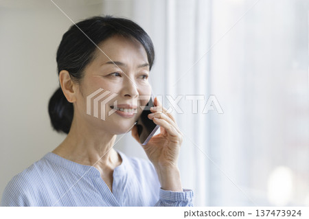 A smiling woman in her late 50s talking on a smartphone A smiling woman in her late 50s talking on a smartphone 137473924