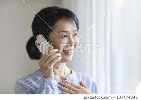 A smiling woman in her late 50s talking on a smartphone A smiling woman in her late 50s talking on a smartphone 137474248