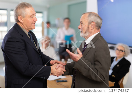 Senior men participants of meeting end business negotiations with handshake 137474287