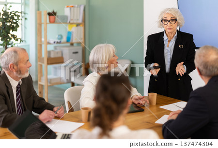 Female leader, trainer talking to group of people, brainstorming, discussing ideas in auditory 137474304