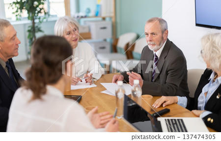 Elderly man leading meeting with senior colleagues at table 137474305