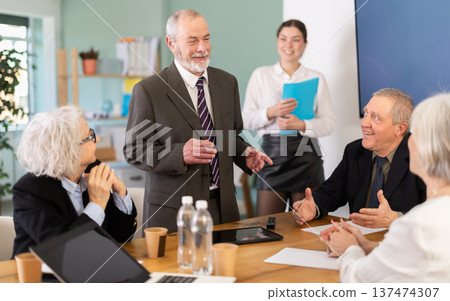 Senior male speaker shares happy news, makes participants laugh 137474307